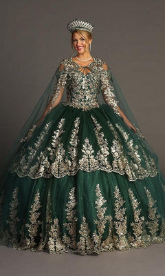 A woman stands against a plain background wearing the Quinceanera Dress CHF3083 By Chicas—an exquisite emerald green ballgown crafted from glitter tulle, detailed with gold embroidery, and paired with a matching cape and jeweled crown, evoking the regal elegance of a classic Quinceañera ensemble.