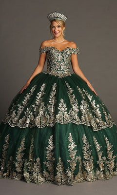 A woman stands against a plain background wearing the Quinceanera Dress CHF3083 By Chicas—a glitter tulle ballgown with gold embroidery, off-the-shoulder sleeves, and a matching crown.