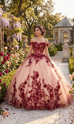 A woman in the Quinceanera Dress CHF3088 by Chicas, an off-the-shoulder burgundy and nude tulle ballgown adorned with red floral embroidery, stands in a garden surrounded by roses and wisteria, with a stone building in the background.