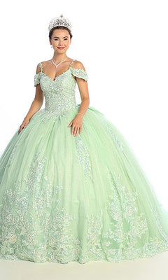 A woman wearing the Quinceanera Dress CHF3089 by Chicas—a light green cold shoulder gown with floral embroidery—paired with a tiara, necklace, and earrings, standing against a white background.
