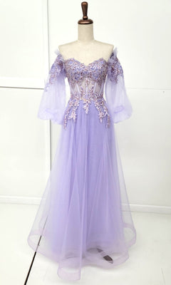 The Long Sleeve Long A-Line Prom Dress: Chicas CHF3093, shown on a dress form, features a lavender hue, sheer puff sleeves, floral appliqué bodice, and a flowing tulle skirt.