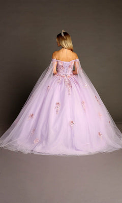Wearing the Quinceanera Dress CHF3095 by Chicas, a woman stands facing away against a plain backdrop; the lilac ballgown features off-the-shoulder sleeves and delicate floral appliques.