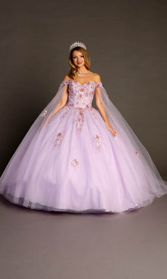 A person wearing the Quinceanera Dress CHF3095 by Chicas—with delicate floral appliques, off-the-shoulder sleeves, a voluminous lilac tulle skirt, and a sparkling tiara—stands gracefully in front of a plain grey background.