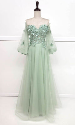 The Chicas CHF3096 Long Sleeve Long Prom Ball Gown in sage green features an off-the-shoulder design, sheer puff sleeves, a floral appliqué bodice, and a flowing floor-length tulle skirt displayed on a dress form.