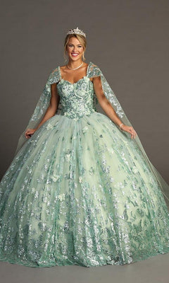 A woman wearing the Quinceanera Dress CHF3097 By Chicas in sage—a sequin-embellished ball gown with sheer cape sleeves and glitter tulle accents—paired with a tiara and pearl necklace, stands against a plain gray background.