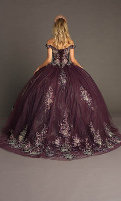 A woman wears the Quinceanera Dress CHF3099 by Chicas—a purple off-the-shoulder ballgown skirt adorned with delicate floral embroidery and paired with a sparkling tiara—standing with her back to the camera against a plain background, capturing the elegance of a classic Quinceanera look.