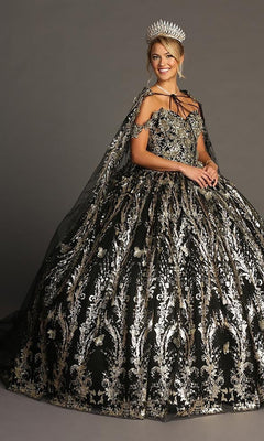 A woman wearing the Quinceanera Dress CHF3101 by Chicas—an ornate black ball gown adorned with metallic-silver embellishments and a dramatic tulle skirt—paired with a matching cape and a large silver crown, stands against a plain background.