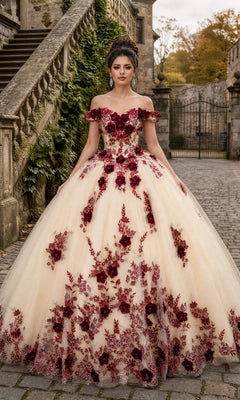 A woman in the Quinceanera Dress CHF3111 By Chicas, featuring burgundy and nude colors with red 3D floral accents, stands outdoors on a stone pathway near stairs and an ornate iron gate.
