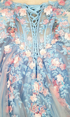 Close-up of the Quinceanera Dress CHF3117 By Chicas featuring a blue lace-up bodice embellished with delicate pink and blue 3D floral appliques and sheer tulle fabric—ideal for a magical quinceanera or an enchanting tulle ballgown ensemble.