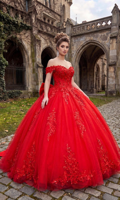 A woman in the Quinceanera Dress CHF3130 By Chicas, a striking red off-the-shoulder gown, stands on cobblestone near a stone building with arched windows and greenery, the tulle ballgown skirt billowing gracefully around her.