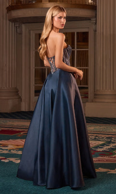 Woman in a blue evening gown with a high slit, standing in an elegant interior setting.