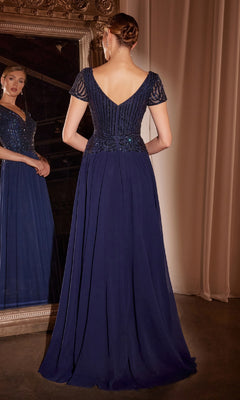 A woman in the Ladivine CL07 Long Flowy Navy Formal Dress with an embellished bodice stands facing a mirror, her back to the camera, in an elegant room with draped curtains.