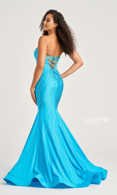 A woman stands sideways in the Colette Strapless Long Glitter Prom Dress CL5106, showing off its bright blue mermaid silhouette, lace-up back, silver sequin accents, and flared glitter print.