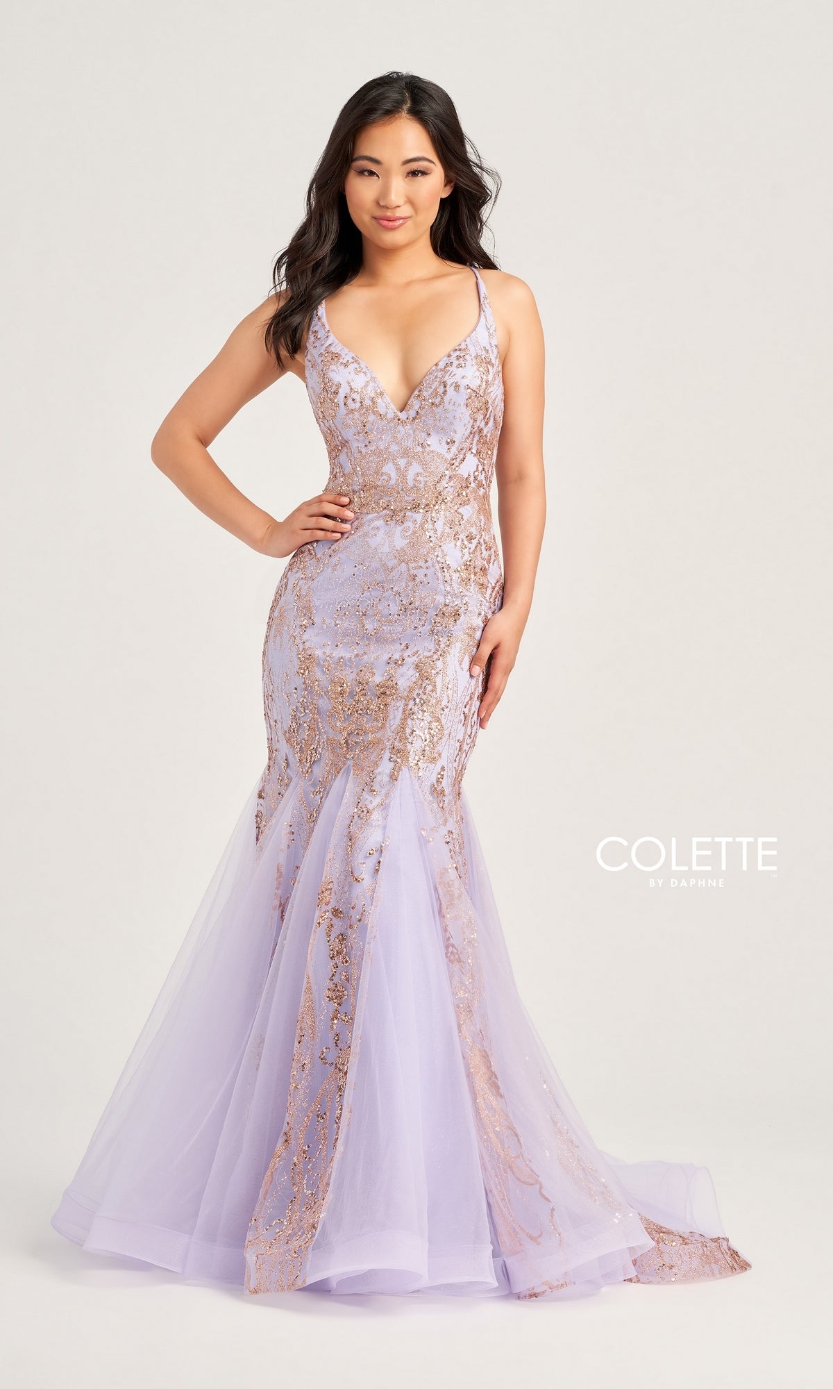 A woman poses with one hand on her hip against a light background, wearing the Colette Long Glitter Mermaid Prom Dress CL5109 in lavender with gold sequin detailing. The text 