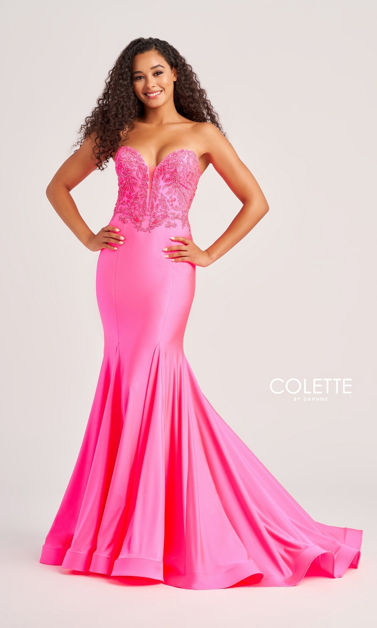 A woman wears the Colette Strapless Long Mermaid Prom Dress CL5112 in bright pink, featuring a lace-detailed bodice and a fitted mermaid silhouette, posed against a plain light background.