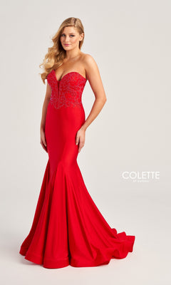 A woman wears the Colette Strapless Long Mermaid Prom Dress CL5112, featuring a fitted red mermaid silhouette and floral beaded bodice, standing against a light background. The "Colette by Daphne" logo is visible.