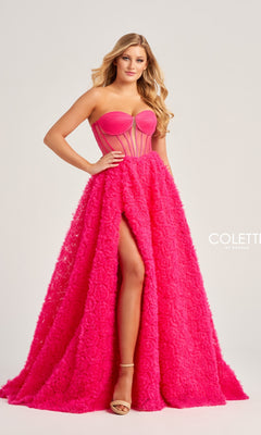 A woman wears the Bustier Colette Long A-Line Prom Ball Gown CL5114—hot pink with a sheer strapless bodice, textured voluminous skirt, high slit—and pairs it with nude heels.