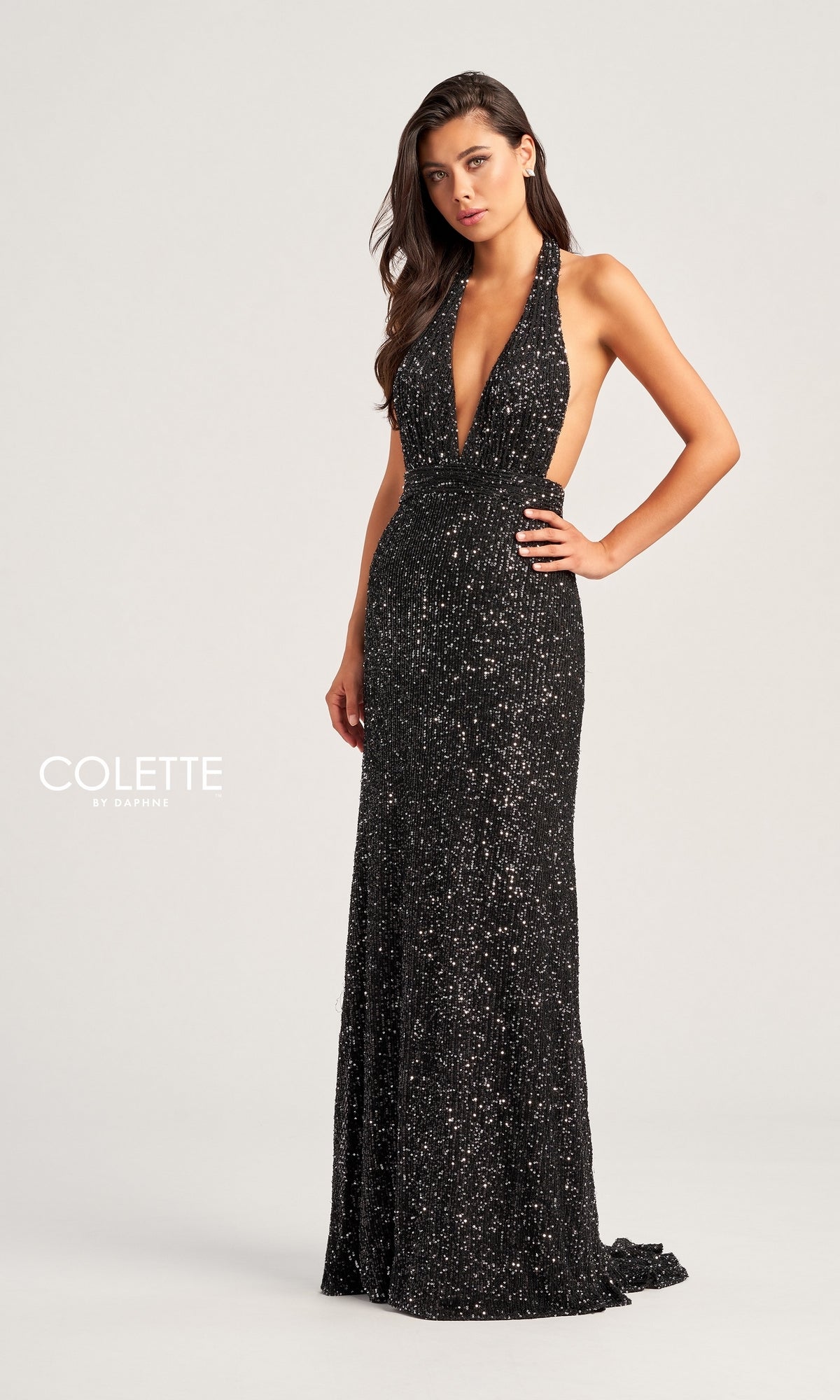 A woman poses in the Colette Long Sequin Halter Prom Dress CL5115, a sleeveless, floor-length black gown with shimmering sequins and a deep V-neckline, set against a plain light background for an elegant look.