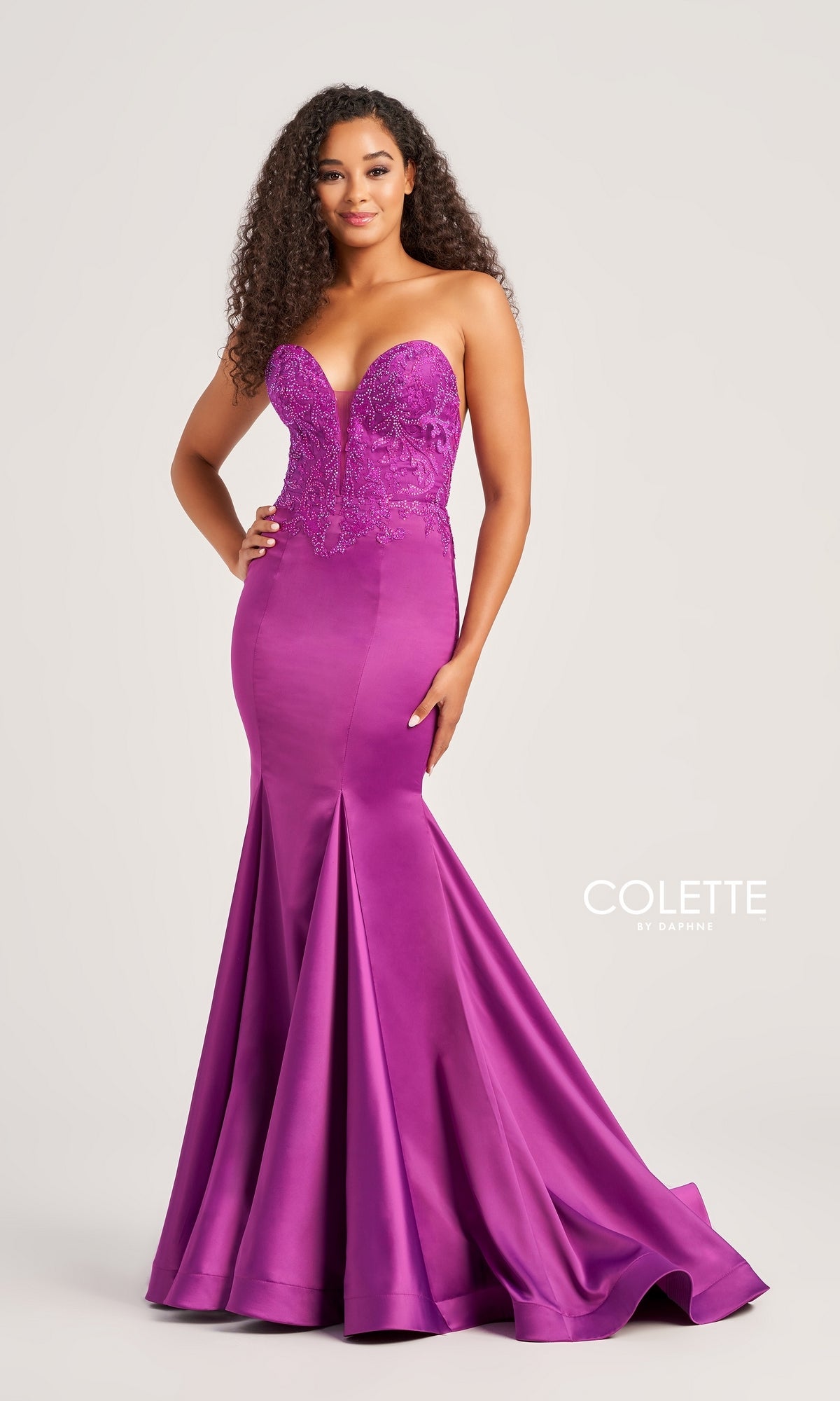 A woman wears the Strapless Colette Long Mermaid Prom Dress CL5116, featuring a beaded sweetheart bodice and flared satin skirt, standing against a plain background. 