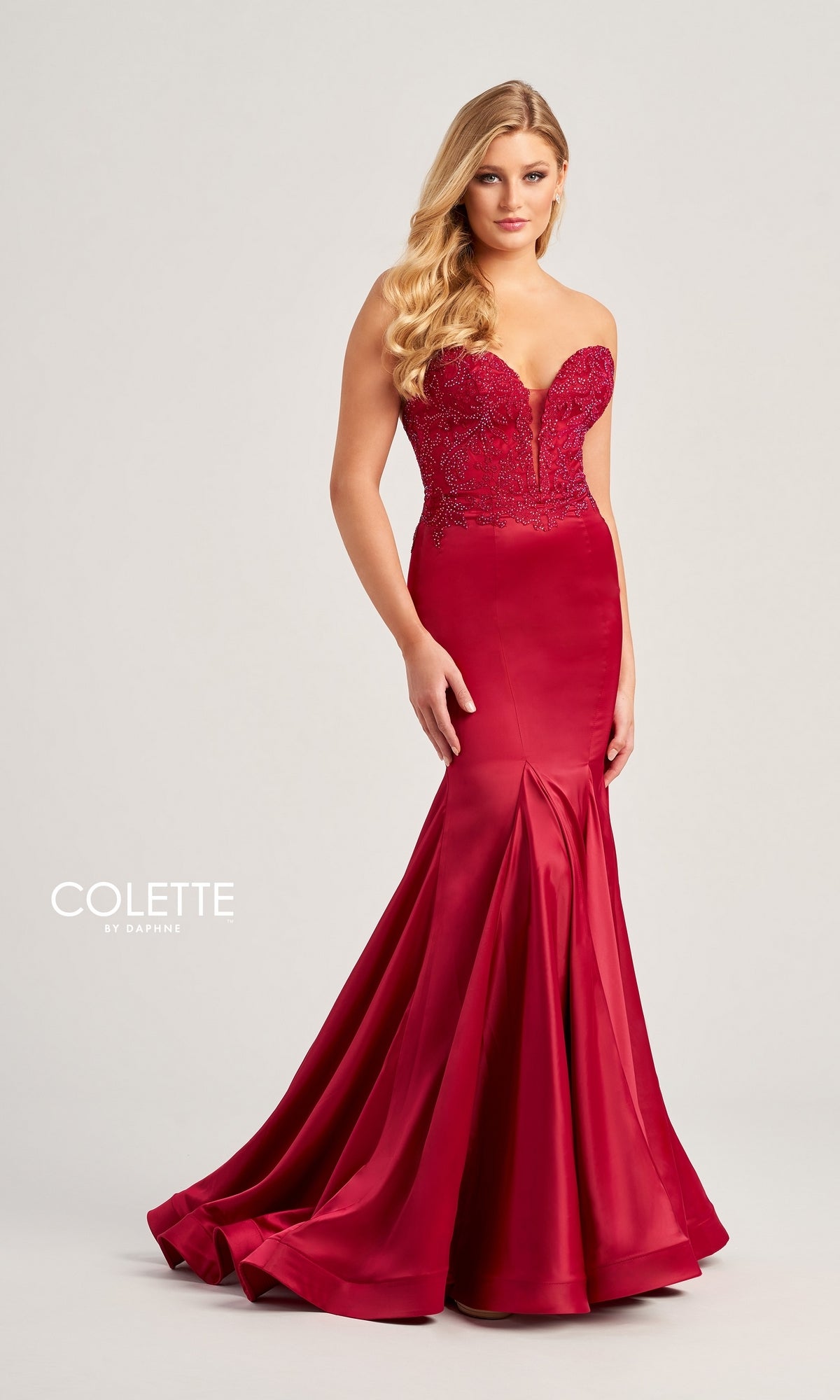 A woman wears the Strapless Colette Long Mermaid Prom Dress CL5116 in red, featuring a beaded lace sweetheart bodice, fitted mermaid silhouette, and flared hem, standing against a plain light background.