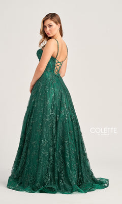 A woman wearing the Colette Glitter-Tulle Long Prom Ball Gown CL5117 in emerald green, featuring an a-line silhouette, corset-style open back, and sequin details, faces slightly away from the camera. "Colette by Daphne" logo is visible.