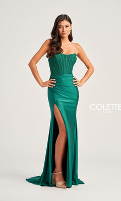 A woman models the Strapless Colette Long Designer Prom Dress CL5158 in emerald green, with a beaded corset bodice and thigh-high slit, standing against a plain background.