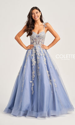 A woman stands smiling against a plain background in the Metallic-Lace Colette Long Tulle Prom Dress CL5165, featuring light blue tulle, floral lace details, and a corset bodice.