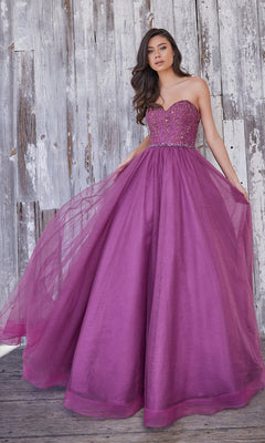 Wearing the Colette Strapless Sweetheart Prom Ball Gown CL5193, a woman poses in front of a weathered wooden wall, showcasing the floor-length purple tulle skirt and elegant silhouette.