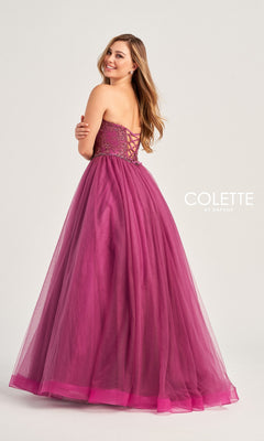 A woman smiles over her shoulder in the Colette Strapless Sweetheart Prom Ball Gown CL5193, a magenta tulle dress with a lace-up back. The "Colette by Daphne" logo is visible on the right.