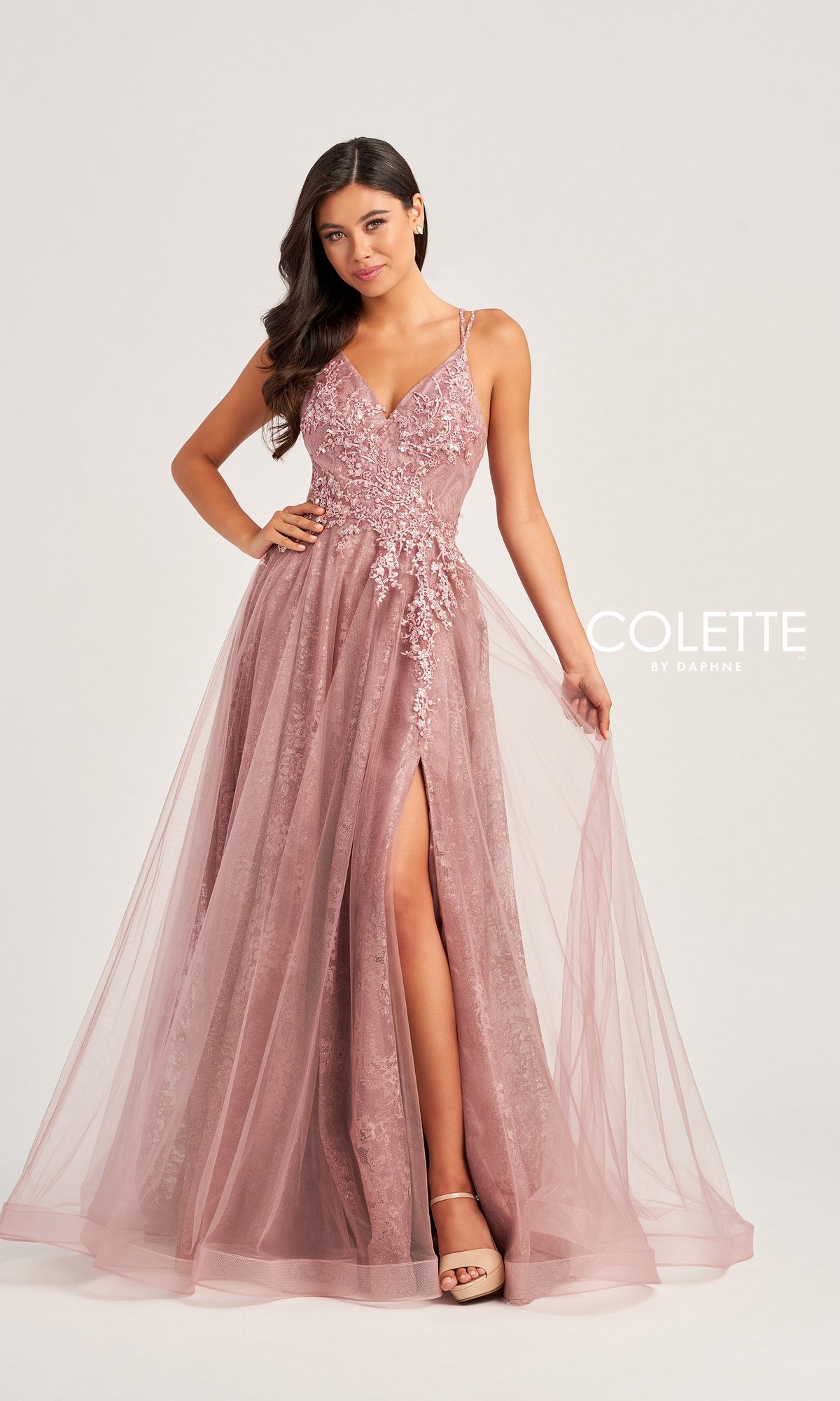 A woman poses against a plain background wearing the Glitter-Lace Colette Long Prom Ball Gown CL5197, a mauve, floor-length A-line dress with beaded-lace floral applique, V-neckline, high slit, and tulle overlay.