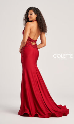 A woman poses in the Lace-Bodice Colette Long Halter Prom Dress CL5206, a backless, floor-length red gown with sparkly lace and floral embellishments, a fitted waist and hips, slight train, and halter neckline.