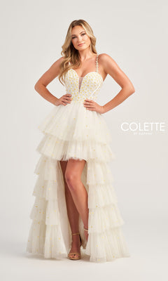 A woman poses in the Colette High-Low Daisy Tiered Prom Dress CL5237, a white prom dress with yellow embellishments and spaghetti straps, against a plain light background.