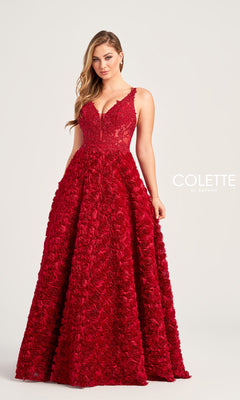 A woman stands against a plain background wearing the Colette Long Red Rosette Prom Dress CL5251, featuring a sleeveless fitted lace bodice, beaded sheer-corset, and a floor-length skirt adorned with 3-D rosettes and floral appliqués.