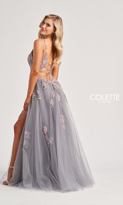 A woman models the Colette CL8130, a lavender long prom dress featuring a tulle skirt, lace-up strappy open back, delicate floral embroidery, lace embellishments, and a thigh-high slit against a plain light background.