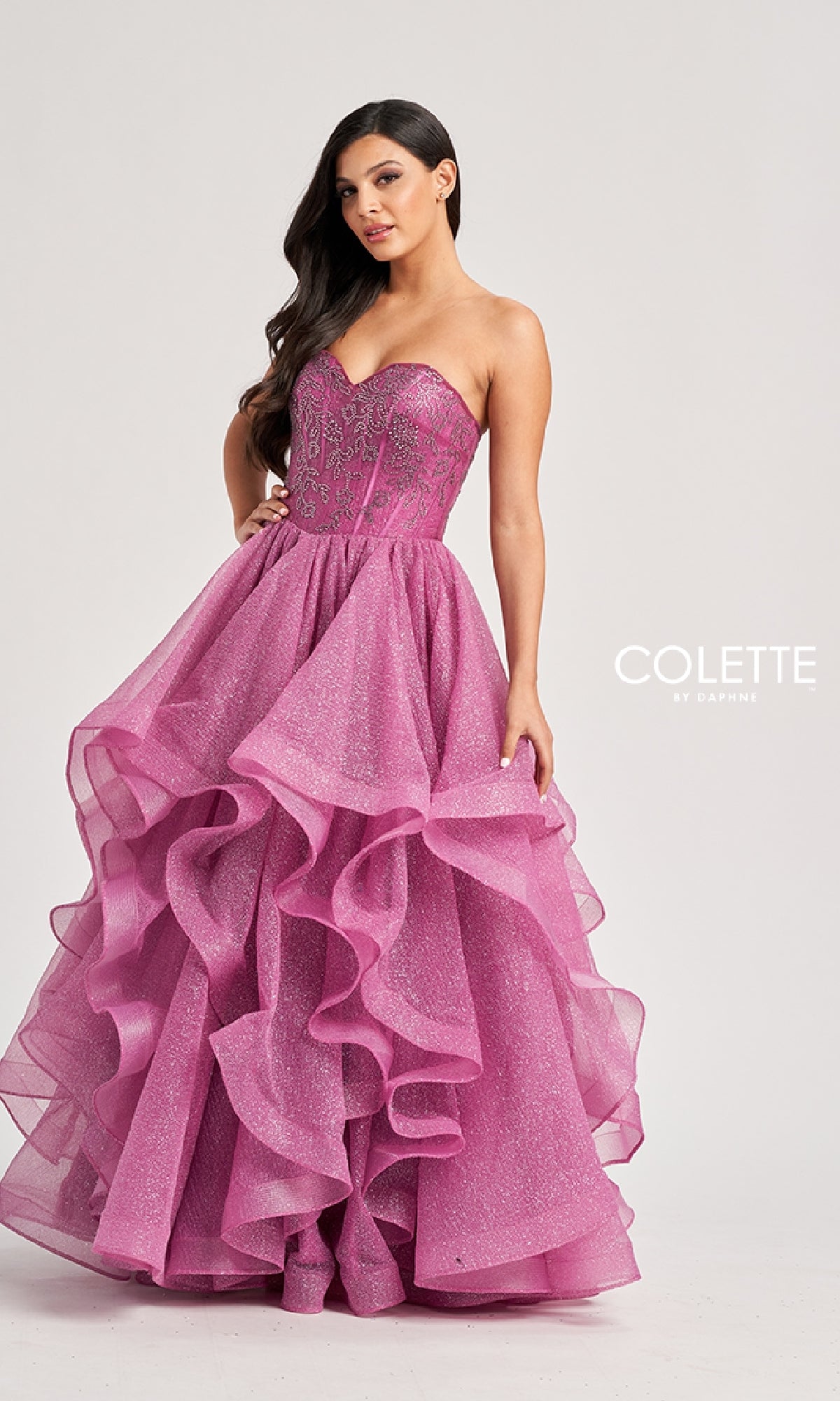 A woman models the Colette CL8200 long prom ball gown, featuring a strapless beaded corset bodice and a ruffle tiered glitter tulle skirt, standing against a plain background.