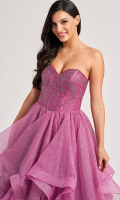 A woman stands smiling at the camera in the Colette CL8200 long prom ball gown, featuring a strapless beaded corset bodice and a ruffle-tiered glitter tulle skirt.