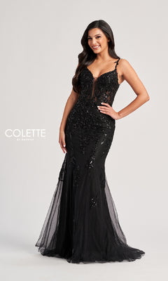A woman smiles with one hand on her hip, wearing the Colette CL8210 Long Prom Dress—a fitted black lace evening gown with a sheer bodice and mermaid silhouette—against a plain light background.