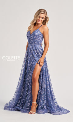 A woman wears the Colette CL8230 long prom dress, a lavender floral sleeveless gown with a high slit and open back, paired with strappy heels. She has long, wavy blonde hair and stands against a plain background.