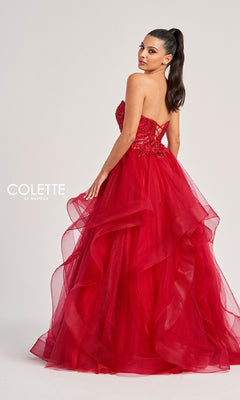 A woman poses with her head turned over her shoulder in the Colette CL8290 long prom dress, featuring a strapless bodice, bright red layered tulle skirt, and lace-up back.