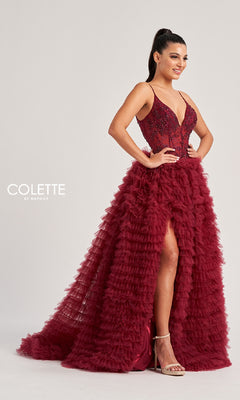 A woman poses against a plain background wearing the Colette CL8330 long prom dress, a sleeveless burgundy gown with a beaded sheer embroidered bodice and tiered ruffled skirt featuring a thigh-high slit.