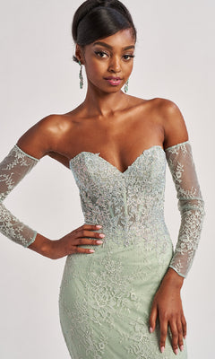Woman wearing the Colette CL8415 Strapless Long Lace Prom Dress in light green, featuring sheer sleeves and embroidered details, poses with one hand on her hip.