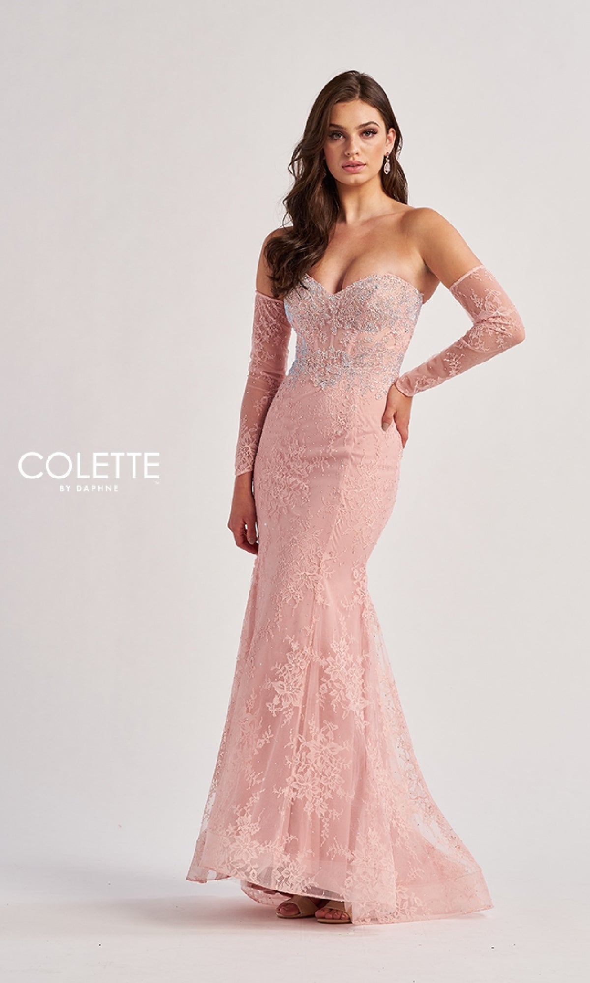 A woman in the Colette CL8415 Strapless Long Lace Prom Dress with matching arm sleeves poses against a plain background. The fitted pink gown features a sweetheart neckline and a subtle train.