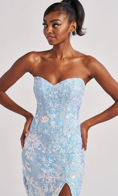 Woman wears the Colette CL8440 Long Prom Dress—a strapless, light blue, iridescent floral gown with a boned corset bodice and sweetheart neckline—posing hands on hips against a plain background.
