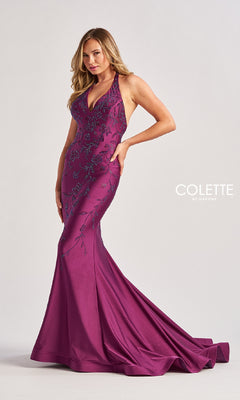 A woman poses in the Colette by Daphne Long Halter Prom Dress (CL8455), a floor-length magenta gown with floral embroidery, sleeveless design, halter v-neckline, and a flared train.