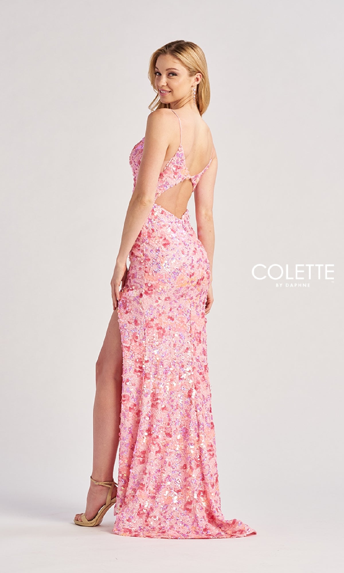 A woman in heels poses against a plain background wearing the fitted Long Prom Dress: Colette CL8465, a pink sequin gown featuring a thigh-high slit and open back, showcasing the 