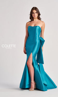 A woman poses against a plain light background wearing the Colette CL8470 Back Bow Strapless Long Prom Dress in teal, featuring a side slit and large bow detail.