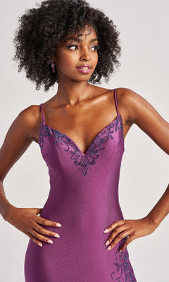 A woman models the Colette CL8485 long prom dress, a sleeveless purple bodycon gown with beaded accents on the neckline and hip, standing with hands on hips against a neutral background.