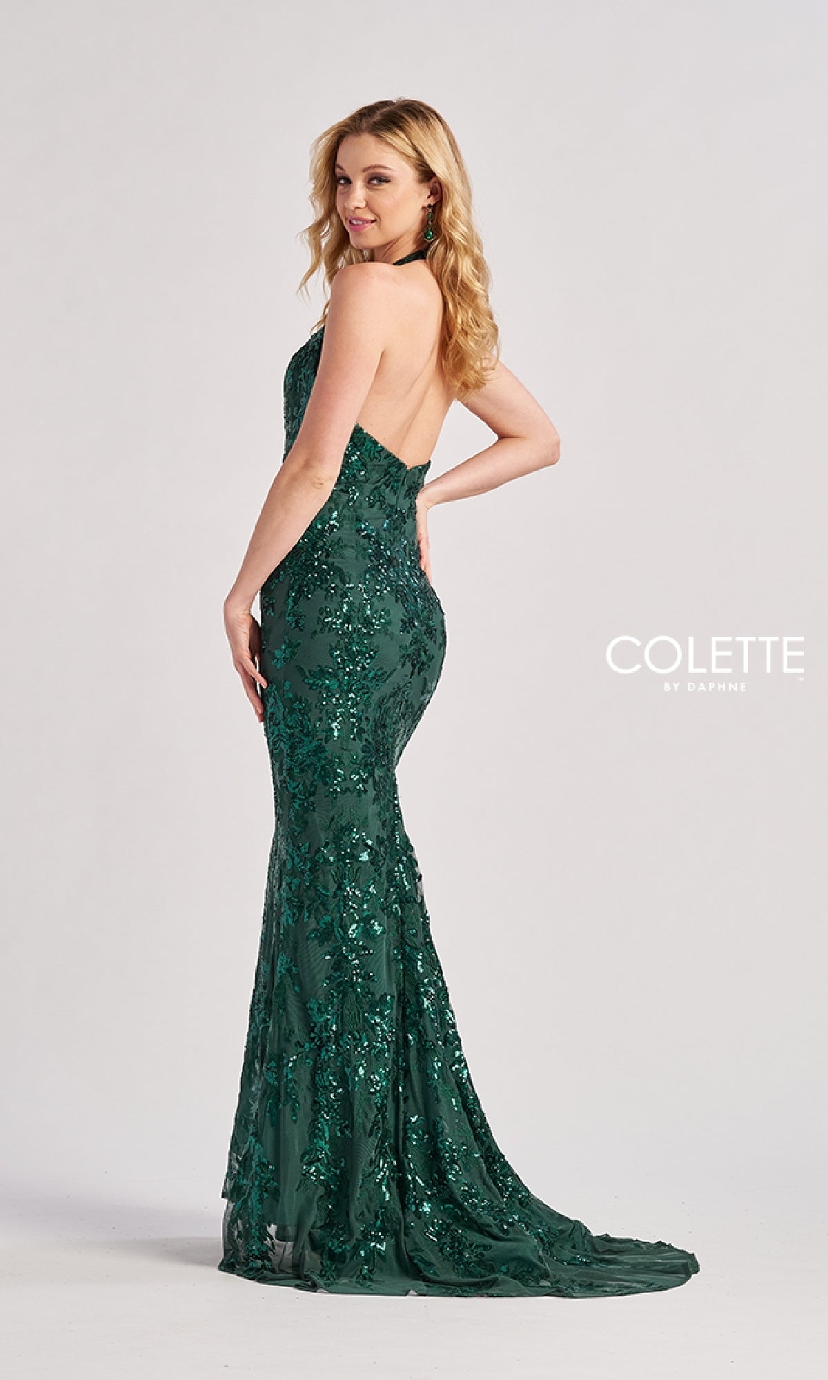 A woman models the Colette CL8495 long prom dress, a strapless, floor-length dark green mermaid gown with sequins and a slight train. 