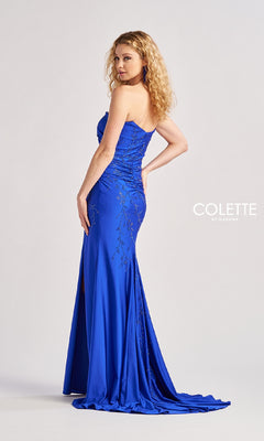 A woman poses sideways in the Long Prom Dress: Colette CL8500, a strapless royal blue gown with sparkly stone accents and a side slit. The floor-length dress stands out against a plain background with the "Colette by Daphne" logo visible.