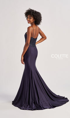 A woman stands against a plain background wearing the Long Prom Dress: Colette CL8515—a dark purple, floor-length mermaid gown with a sweetheart neckline, thin straps, and a beaded bodice.